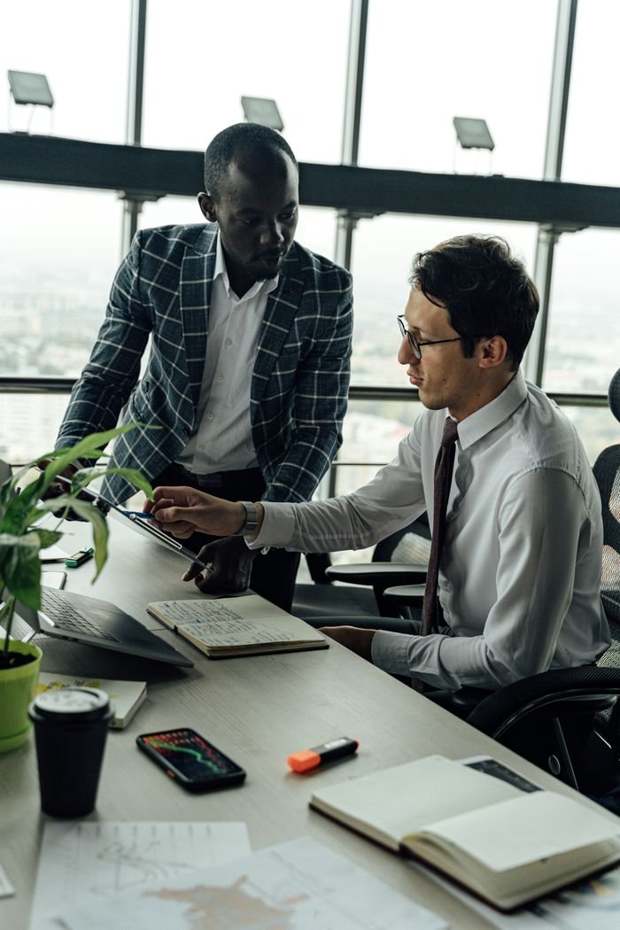 Mastering the First Impression: Your intriguing post title goes here Two businessmen discussing projects in a modern high-rise office setting.